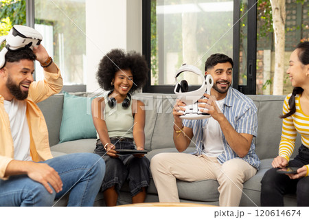 Friends sitting on couch, holding VR headsets, enjoying technology together 120614674