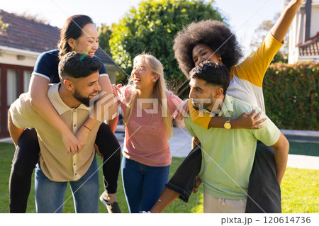 Friends having fun piggybacking and laughing together in backyard gathering 120614736