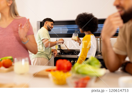 Preparing meal together, diverse friends cooking in kitchen, enjoying fresh ingredients 120614753