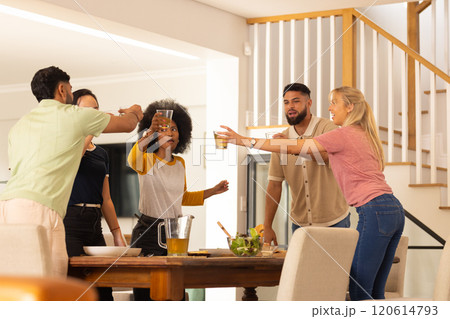 Friends toasting drinks around dining table, enjoying social gathering indoors 120614793