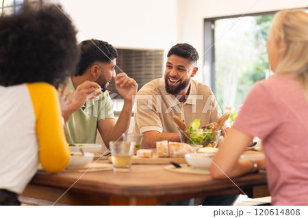 Friends enjoying meal together, laughing and chatting around dining table Friends enjoying meal together, laughing and chatting around dining table 120614808