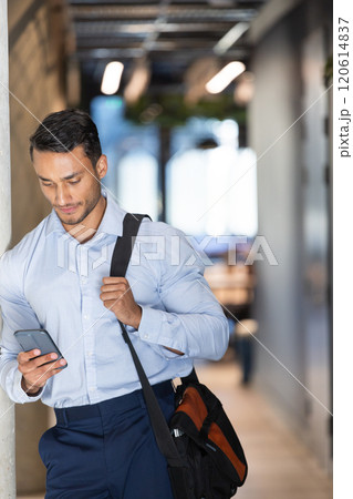 Business professional holding smartphone and carrying bag, walking in office hallway Business professional holding smartphone and carrying bag, walking in office hallway 120614837