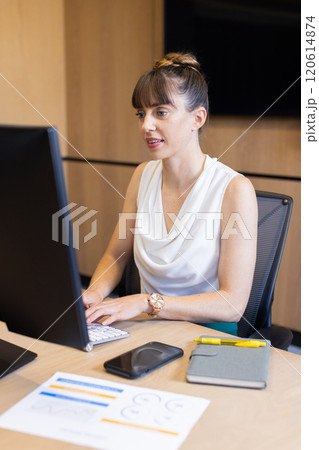 Working on computer, businesswoman typing at desk with documents and smartphone 120614874