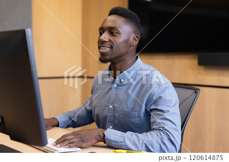 Working on computer, african american man smiling and typing at office desk Working on computer, african american man smiling and typing at office desk 120614875