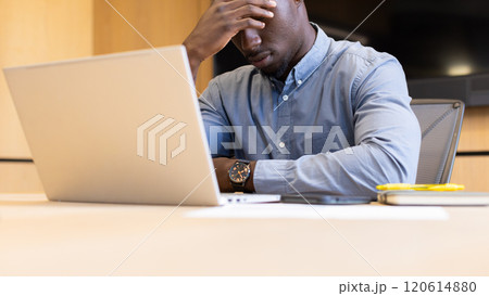 Stressed businessman working on laptop at office desk, holding head in frustration Stressed businessman working on laptop at office desk, holding head in frustration 120614880