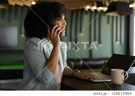 Talking on smartphone, woman using laptop and drinking coffee in modern office 120614964