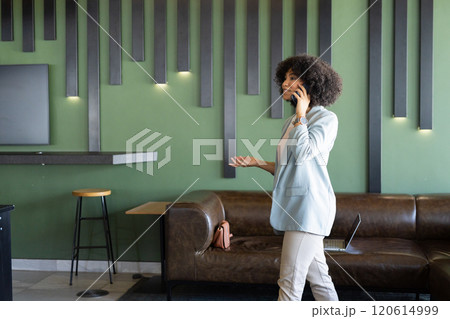 Talking on smartphone, businesswoman standing in modern office with laptop on couch, copy space 120614999