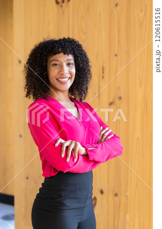 Confident businesswoman in pink blouse standing with arms crossed, smiling 120615516