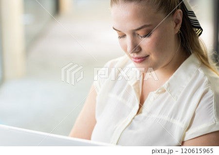Working on laptop, woman focusing on task in modern office setting 120615965