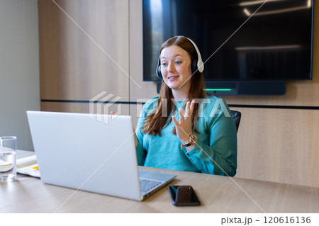 Conducting video call, woman with headset using laptop in modern office 120616136