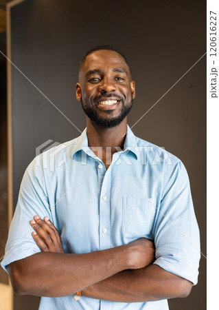 Smiling african american man in blue shirt standing with arms crossed, looking confident Smiling african american man in blue shirt standing with arms crossed, looking confident 120616227