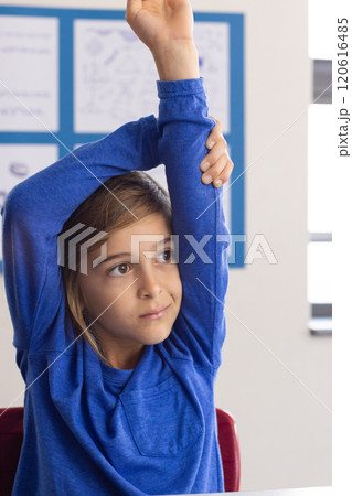 In school, boy raising hand in classroom, participating in lesson 120616485