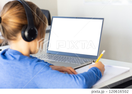In school, boy wearing headphones writing in notebook while using laptop, copy space In school, boy wearing headphones writing in notebook while using laptop, copy space 120616502