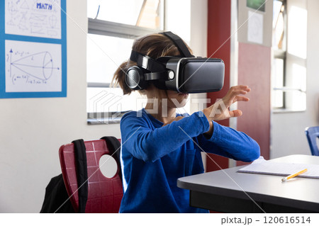 Using VR headset, boy interacting with virtual environment in school classroom Using VR headset, boy interacting with virtual environment in school classroom 120616514