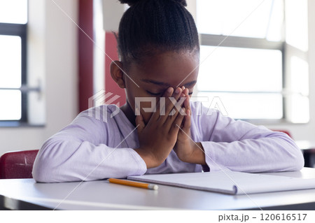 In school, african american girl concentrating with hands on face, pencil and notebook on desk In school, african american girl concentrating with hands on face, pencil and notebook on desk 120616517