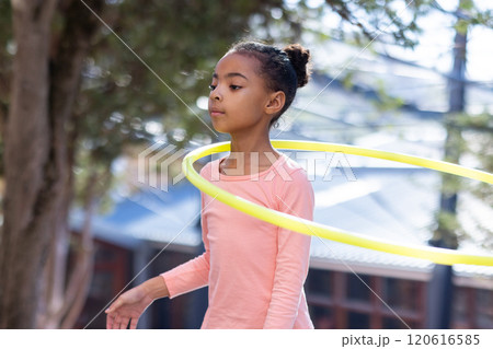 Hula hooping, african american girl enjoying outdoor activity at school playground with friends 120616585