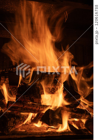 Bright flames and glowing embers consuming stacked firewood in a fireplace, long exposure shot 120616788