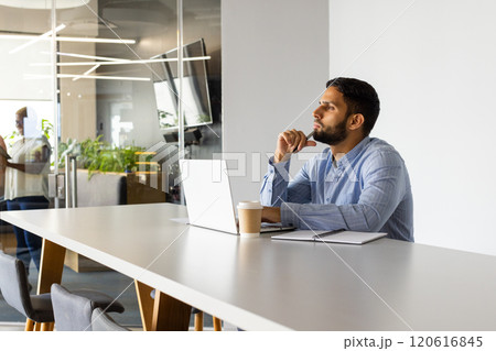 Thinking deeply, man working on laptop with coffee cup in modern office 120616845
