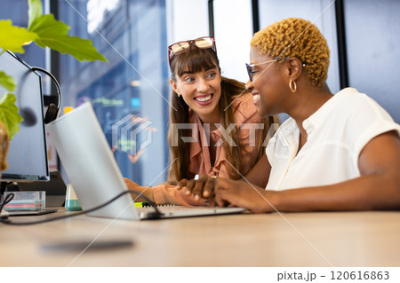 Collaborating at work, two women using laptop and discussing project in office Collaborating at work, two women using laptop and discussing project in office 120616863