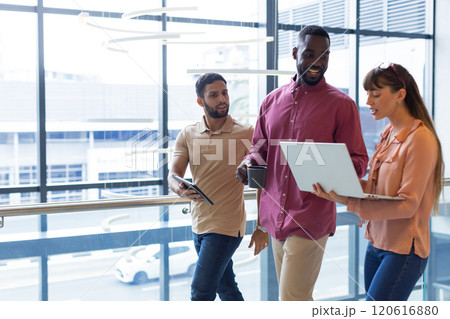 Discussing work, diverse colleagues using laptop and tablet in modern office, copy space 120616880