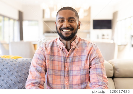 Sitting on couch in living room, smiling indian man enjoying relaxed moment, on video call Sitting on couch in living room, smiling indian man enjoying relaxed moment, on video call 120617426
