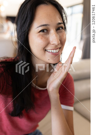 On video call, smiling woman in red shirt posing indoors, at home On video call, smiling woman in red shirt posing indoors, at home 120617461