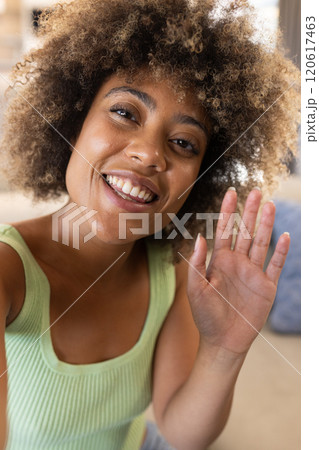 On video call, smiling woman waving at camera, enjoying moment, at home 120617463