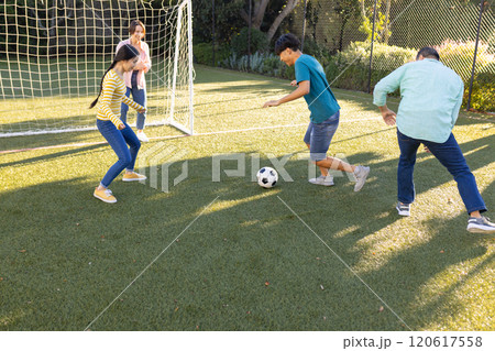 Playing soccer on field, family enjoying outdoor activity together in park 120617558