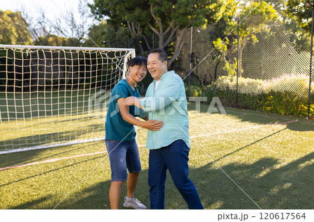 asian father and son playing together on soccer field, enjoying outdoor time 120617564