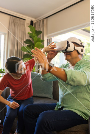 Using VR headset, father exploring virtual reality while daughter assists at home 120617590