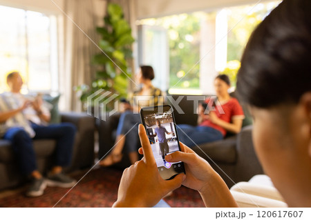 Taking photo with smartphone, person capturing family relaxing on couch 120617607
