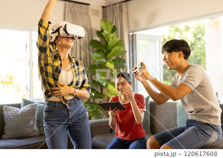 Playing VR game, mother wearing VR headset while family cheering and using tablet 120617608