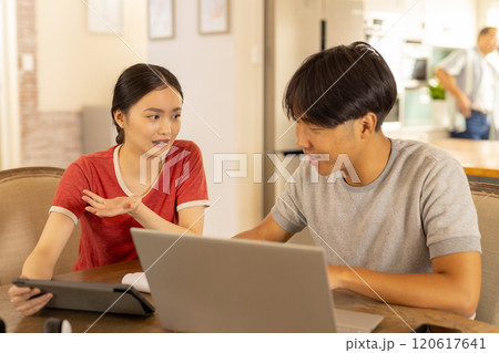 Discussing work, young asian brother and sister using laptop and tablet  at home 120617641