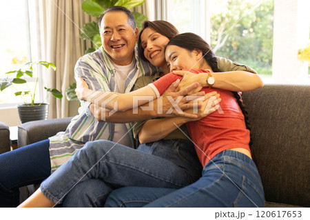 Family hugging and smiling on couch, enjoying quality time together 120617653