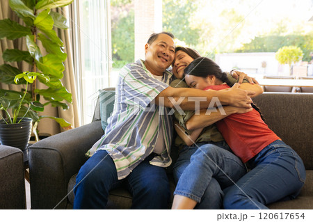 Family hugging and smiling on couch, enjoying quality time together Family hugging and smiling on couch, enjoying quality time together 120617654