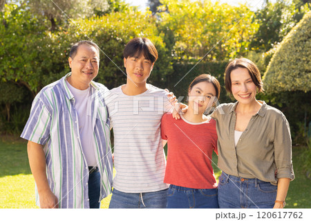 Smiling family standing together in garden, enjoying outdoor time and bonding Smiling family standing together in garden, enjoying outdoor time and bonding 120617762