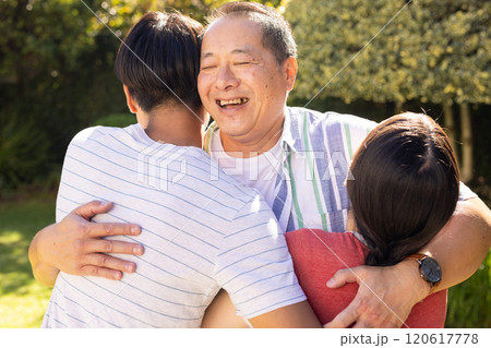 Smiling father hugging teenage son and daughter outdoors, enjoying quality time together 120617778