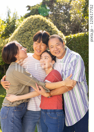 Smiling family with teenagers hugging together outdoors, enjoying quality time in garden 120617782