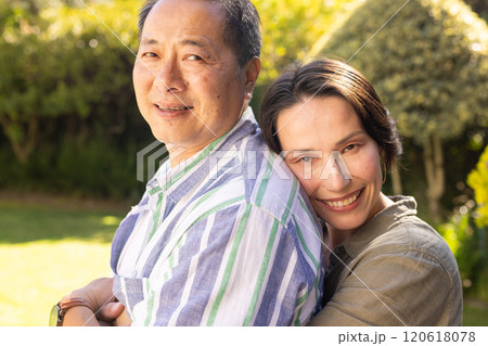 Smiling multiracial middle-aged couple embracing outdoors, enjoying quality time together in garden 120618078