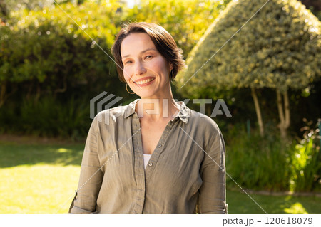 Enjoying sunny day outdoors, smiling middle-aged woman standing in garden 120618079