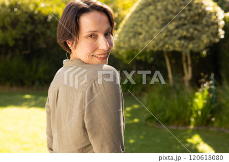 Outdoors, Smiling middle-aged woman in garden, enjoying sunny day and looking over shoulder 120618080