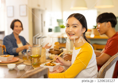 At home, Eating together, asian family enjoying meal and smiling at dining table 120618127