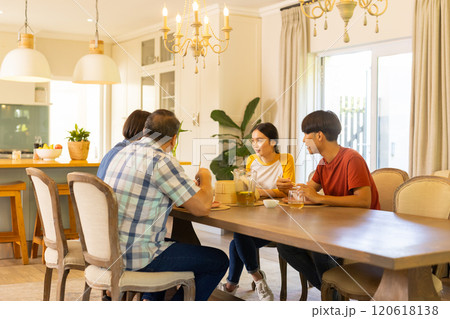 At home, asian family enjoying meal together, sitting at dining table and talking happily 120618138
