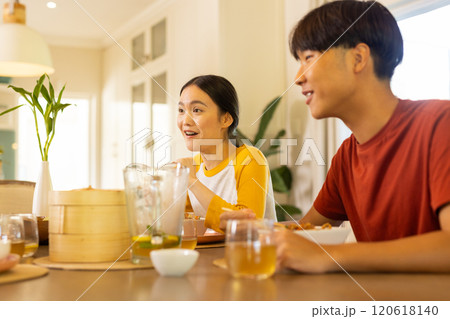 At home, Enjoying family meal, young asian brother and sister smiling and talking at dining table 120618140
