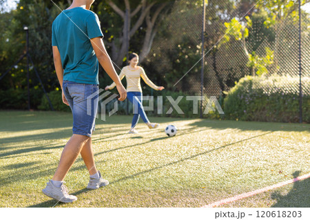 Playing soccer outdoors, two young asian brother and sister enjoying game on sunny day, copy space Playing soccer outdoors, two young asian brother and sister enjoying game on sunny day, copy space 120618203