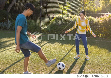 Playing soccer together, young asian brother and sister enjoying outdoor activity on sunny day Playing soccer together, young asian brother and sister enjoying outdoor activity on sunny day 120618204