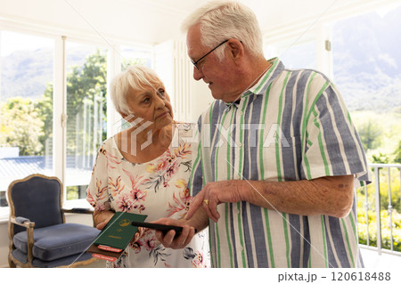 Happy caucasian senior couple holding passports and smartphone in sunny bedroom at home 120618488