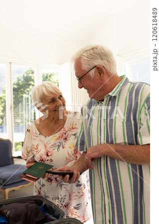 Happy caucasian senior couple holding passports and smartphone in sunny bedroom at home 120618489