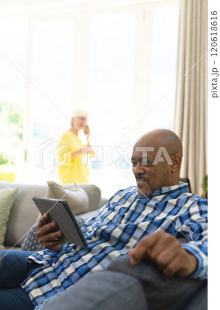 Happy african american senior man having video call in sunny living room, copy space 120618616