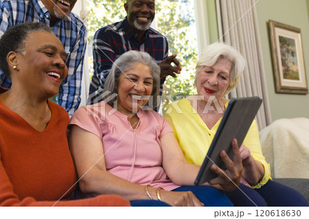 Happy diverse group of senior friends having video call and laughing in sunny living room Happy diverse group of senior friends having video call and laughing in sunny living room 120618630